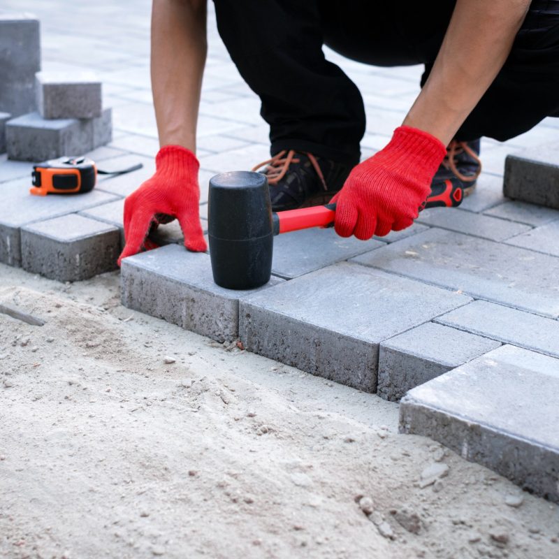 The master in yellow gloves lays paving stones