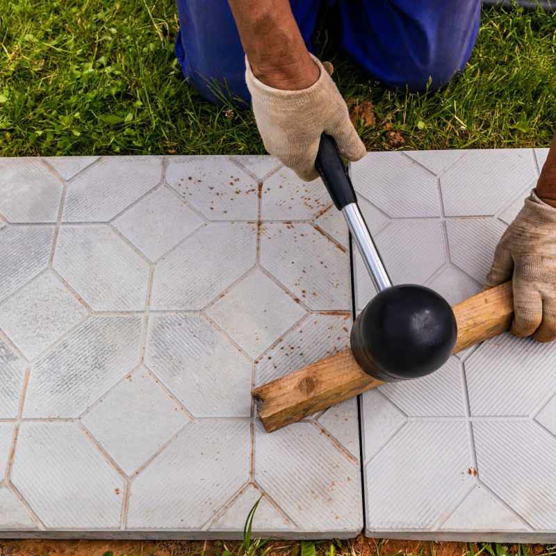 The master lays paving stones in layers. Garden brick pathway paving. Laying concrete paving slabs